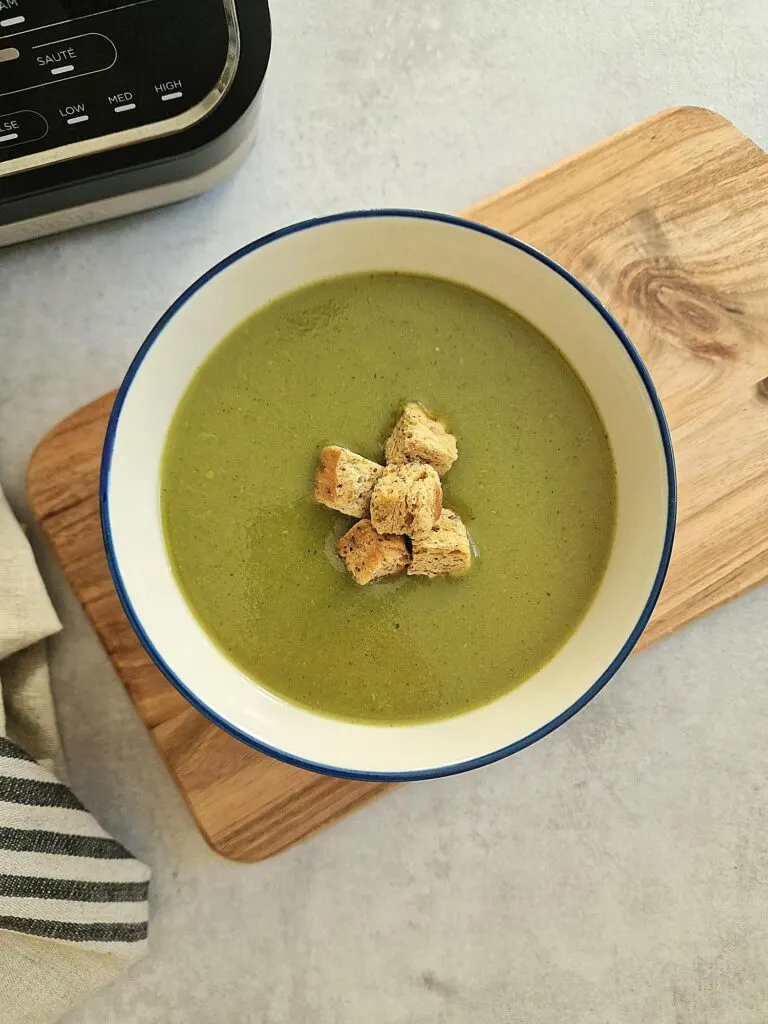 green soup in a bowl next to Ninja soup maker
