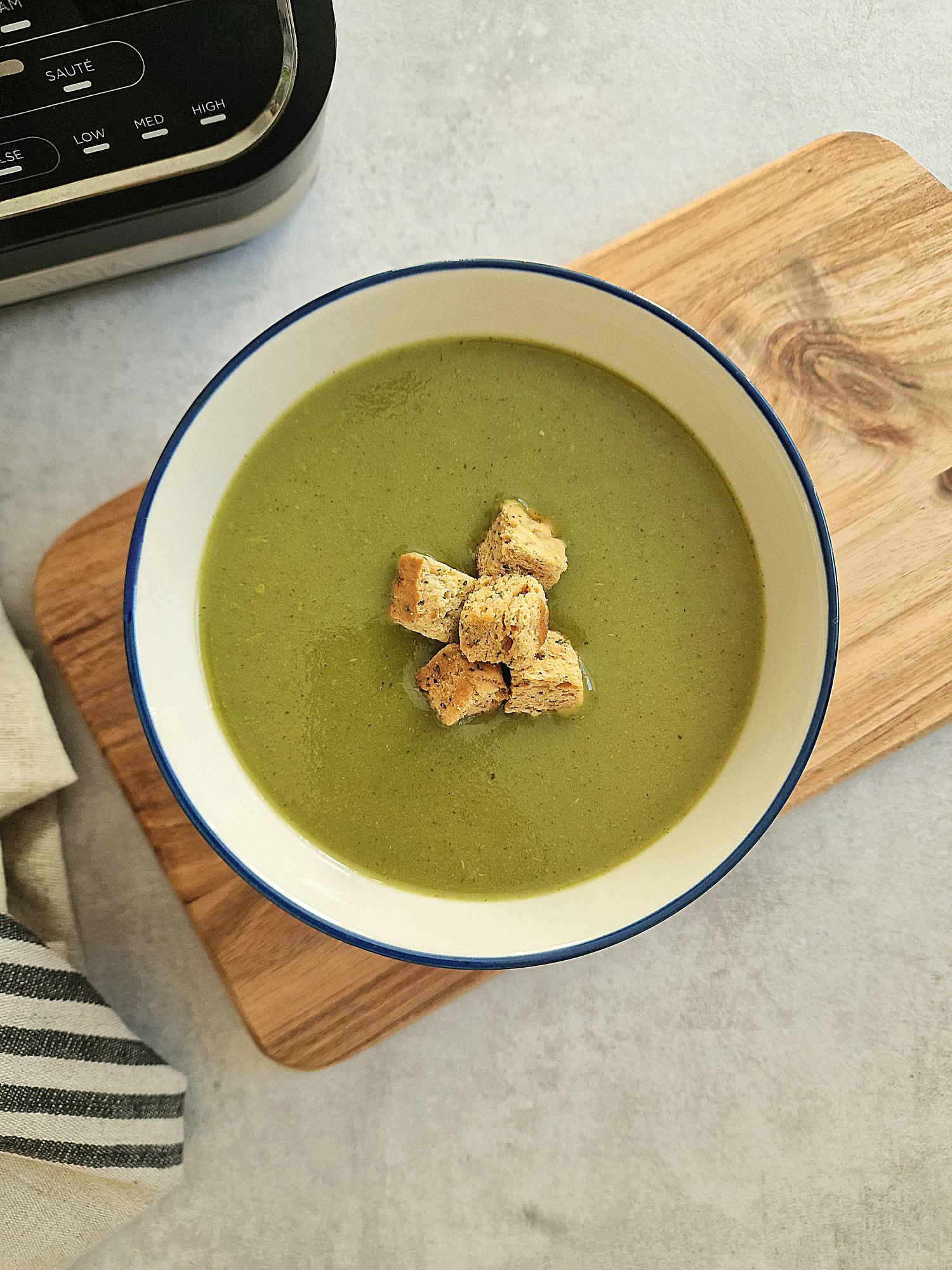 green soup in a bowl next to Ninja soup maker