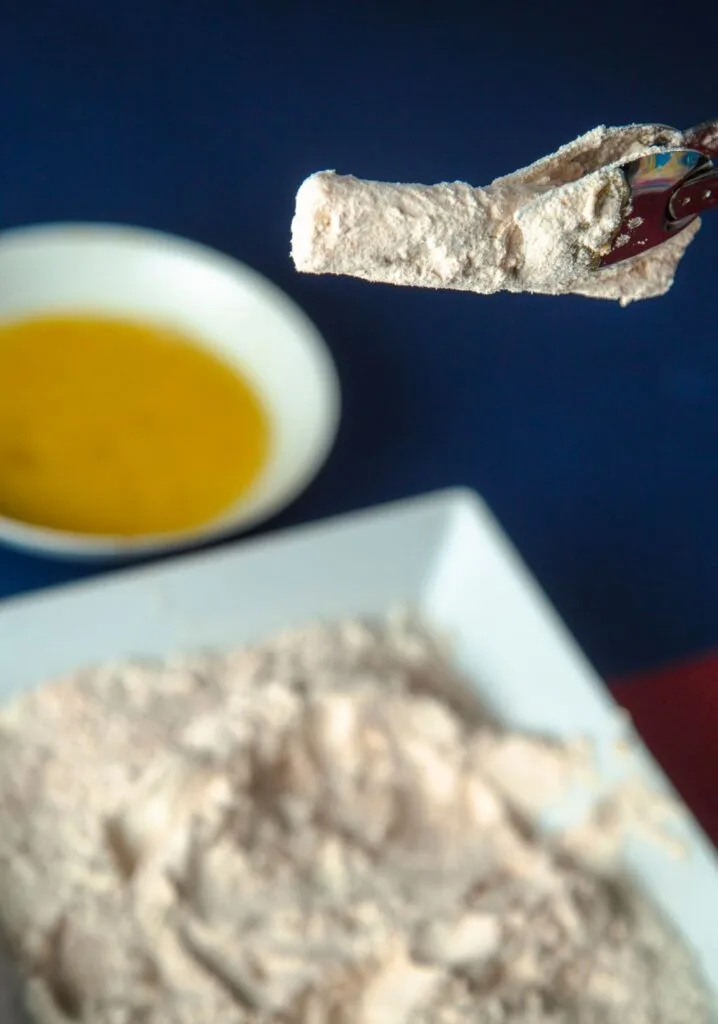 halloumi rolled in flour and held up with tongs