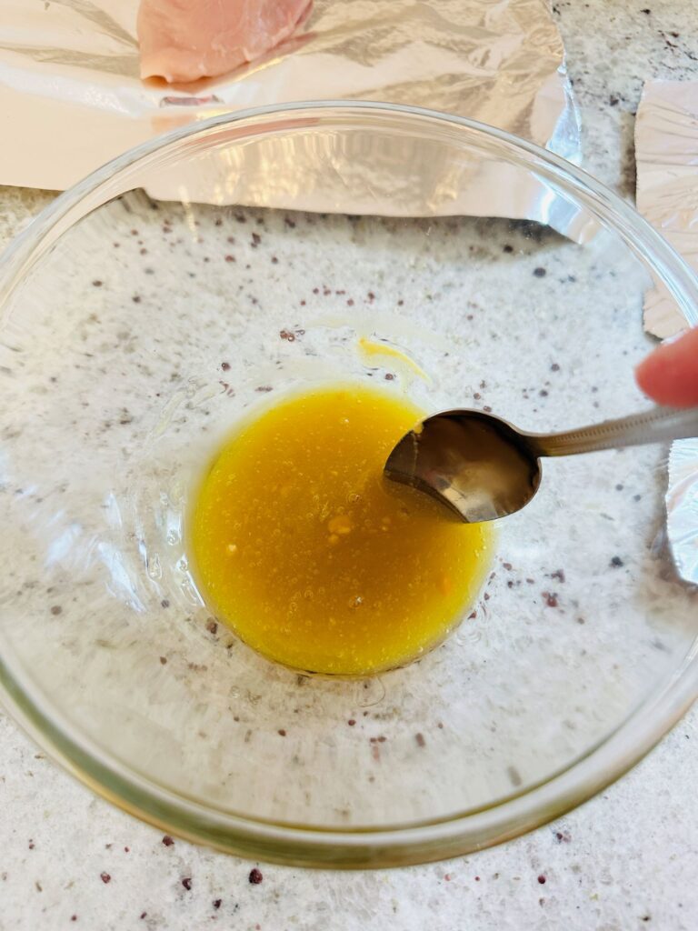 spoon stirring honey, mustard, oil and garlic powder.