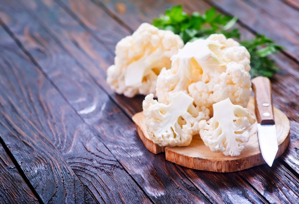 preparing cauliflower by cutting off florets with a sharp knife