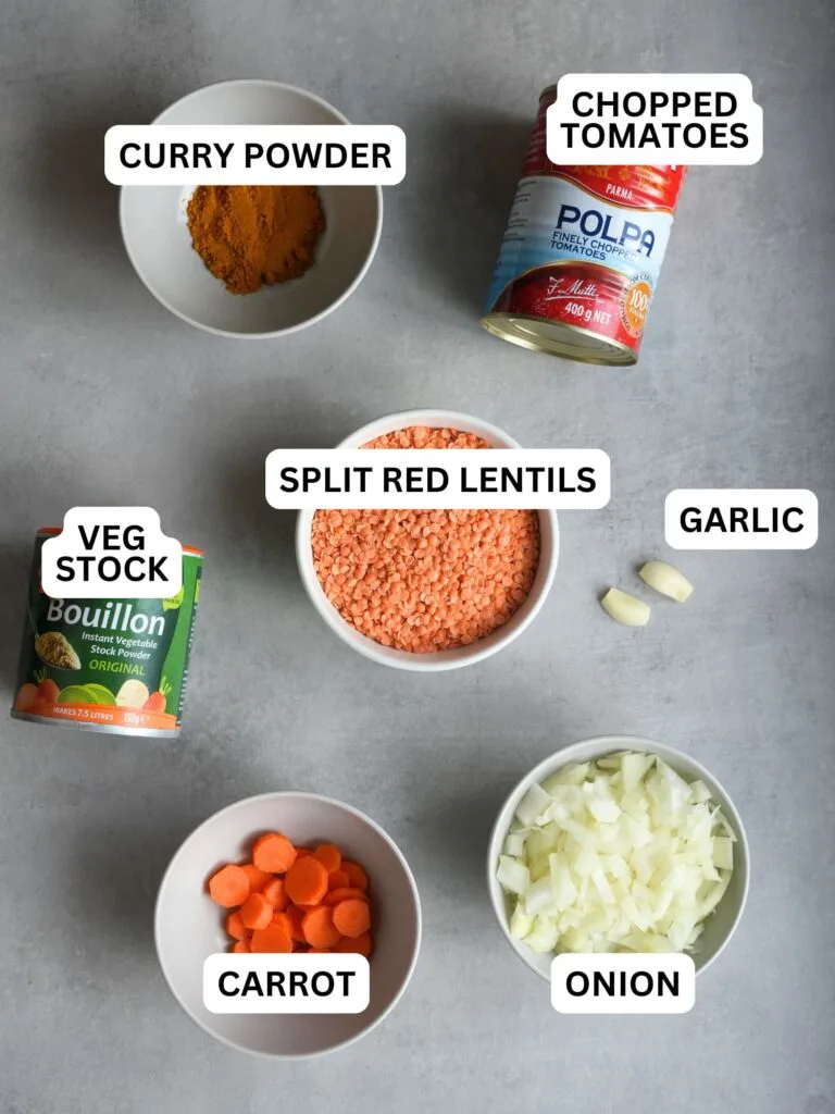 ingredients laid out and labelled for curried lentil soup: curry powder, chopped tomatoes, veg stock, split red lentils, garlic, carrot and onion