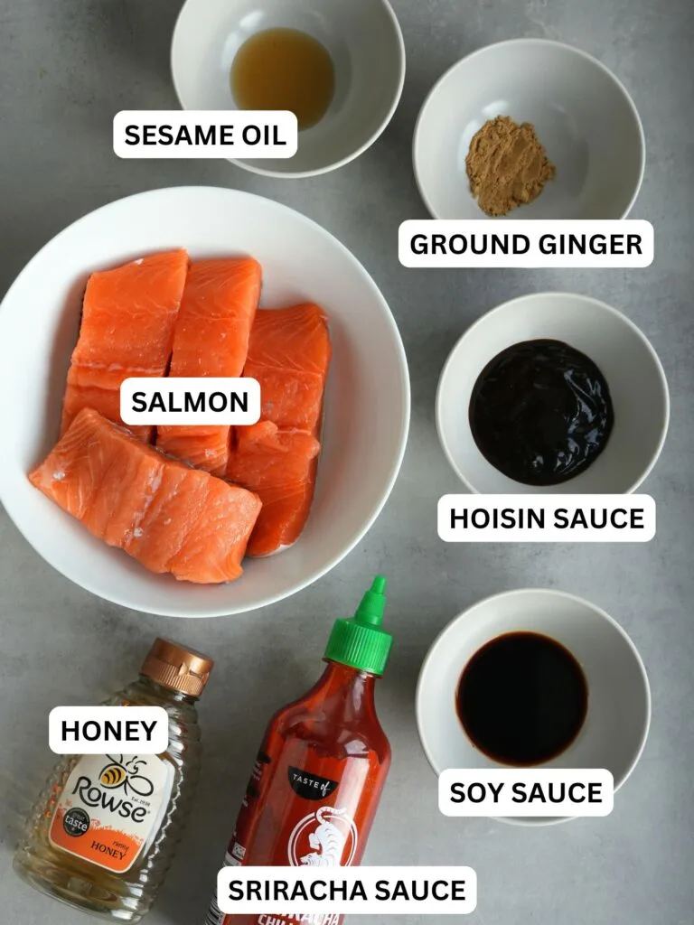 ingredients laid out and labelled for salmon bites cooked in an air fryer: sesame oil, ground ginger, salmon, hoisin sauce, honey, sriracha sauce, soy sauce