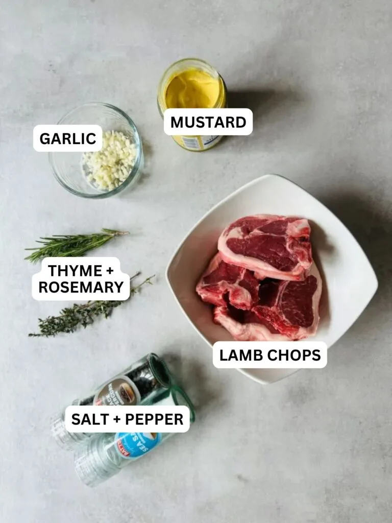 ingredients laid out and labelled for garlic and herb lambs chops: garlic, mustard, thyme, rosemary, lamb chops and salt and pepper