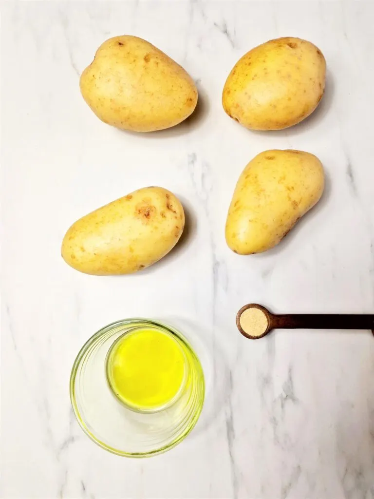 4 potatoes, oil and half teaspoon of garlic granules on a measuring spoon