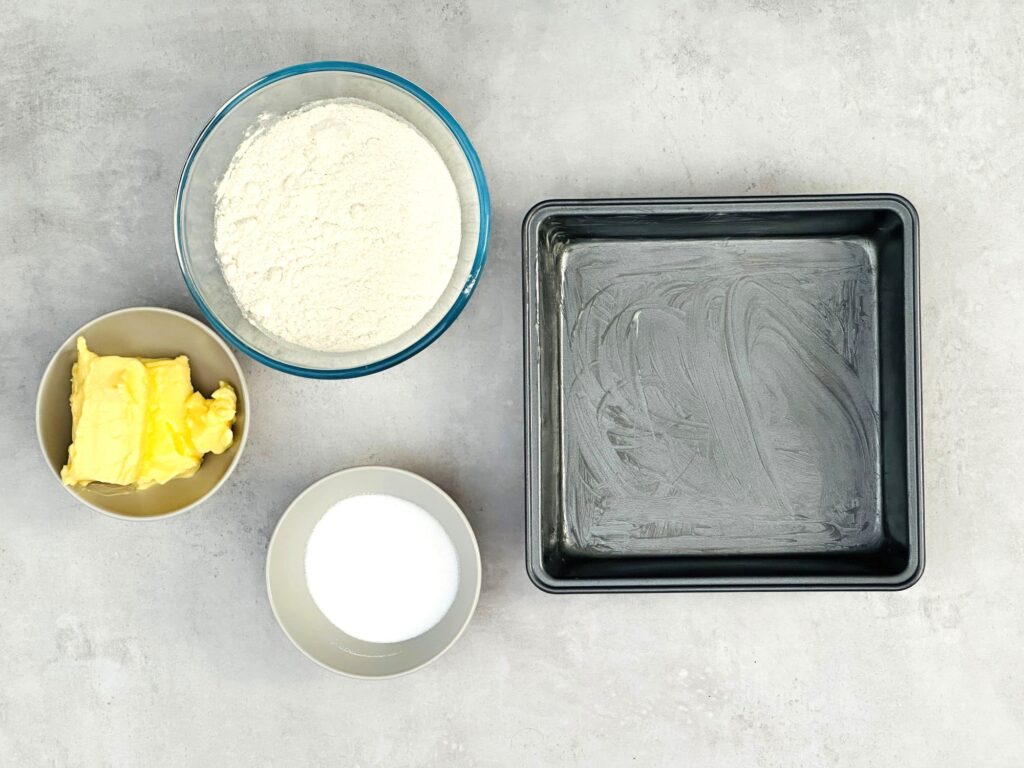 ingredients for air fryer shortbread laid out - butter, sugar, flour and greased baking tin