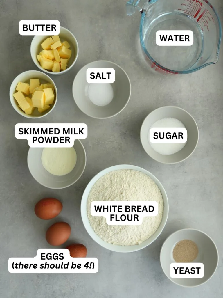 ingredients laid out and labelled for bread maker brioche: butter, water, salt, skimmed milk powder, sugar, white bread flour, eggs, yeast