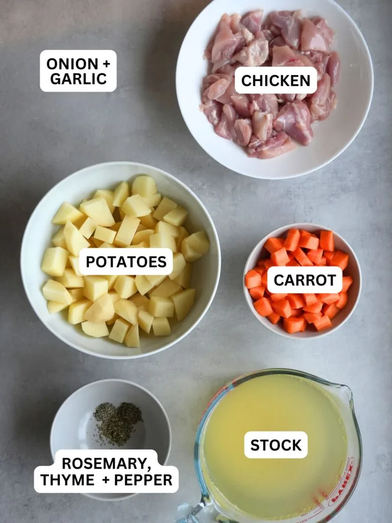 ingredients laid out and labelled for chicken and potato soup: onion and garlic, chicken, potatoes, carrot, rosemary, thyme and pepper and stock