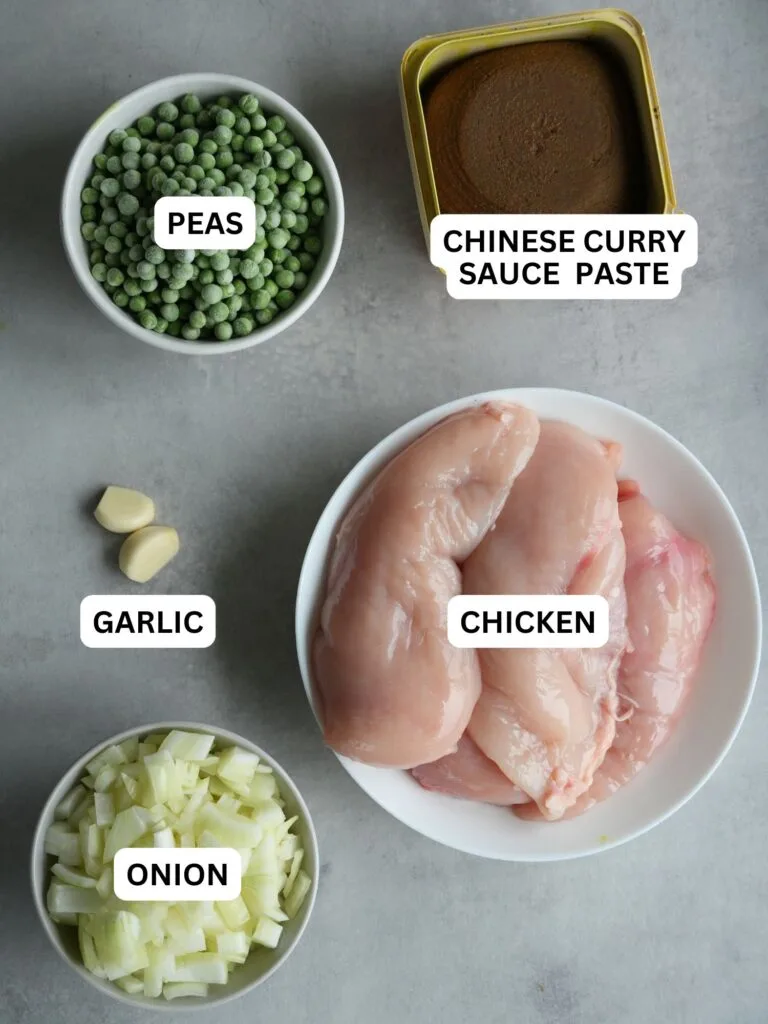 ingredients laid out and labelled for making chinese chicken curry in a slow cooker: frozen peas, chinese curry paste, garlic, chicken, onion