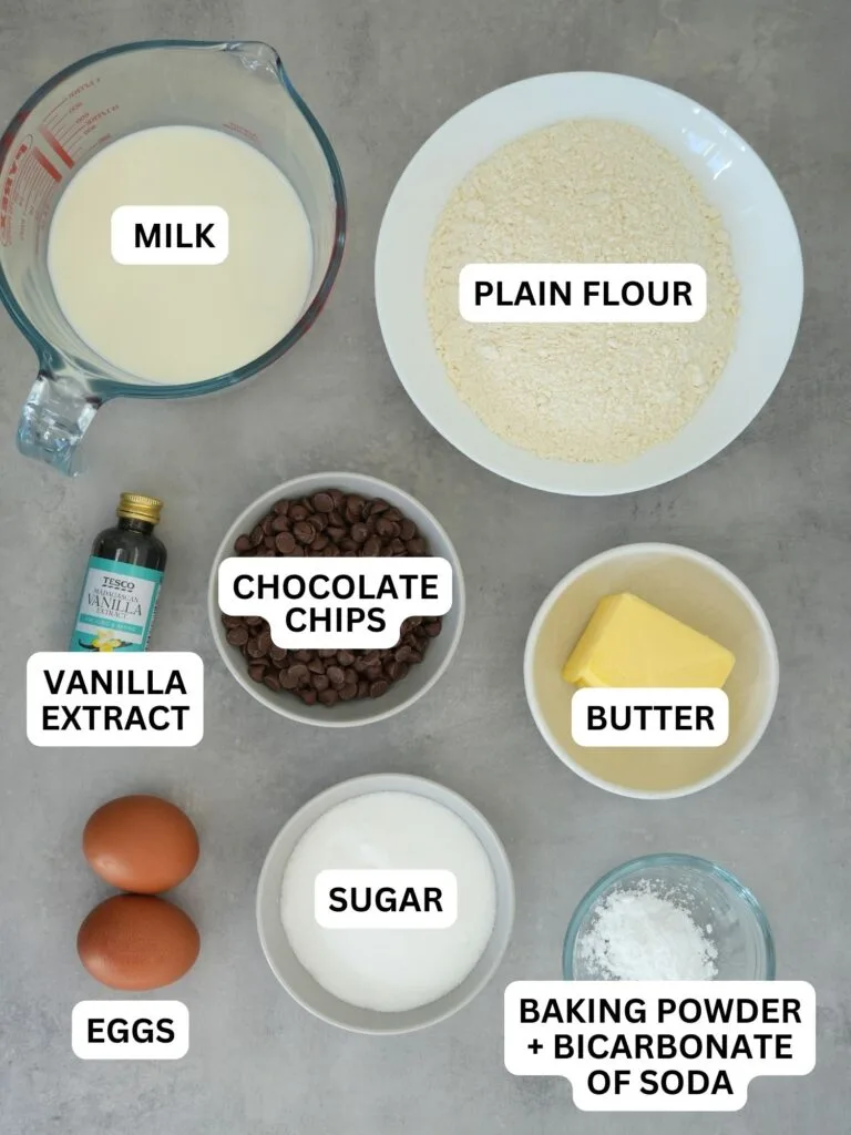 ingredients laid out and labelled for chocolate chip muffins: milk, plain flour, vanilla extract, chocolate chips, butter, eggs, sugar, baking powder + bicarbonate of soda