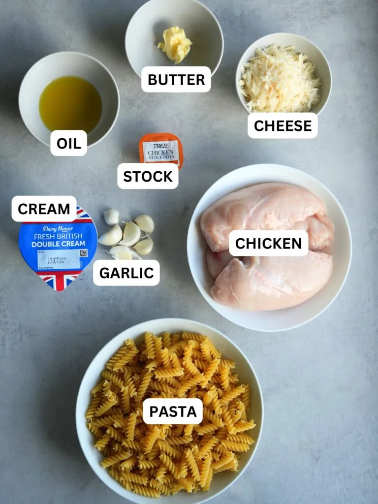labelled ingredients laid out for creamy garlic chicken pasta: oil, butter, cheese, stock, cream, garlic, chicken, pasta
