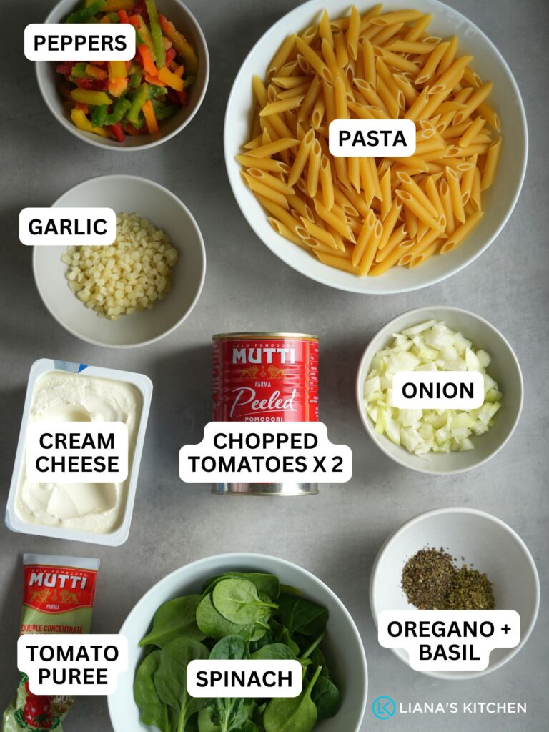 ingredients laid out and labelled for making creamy tomato pasta: peppers, pasta, garlic, cream cheese, tin chopped tomatoes x 2, onion, tomato puree, spinach, oregano and basil dried herbs