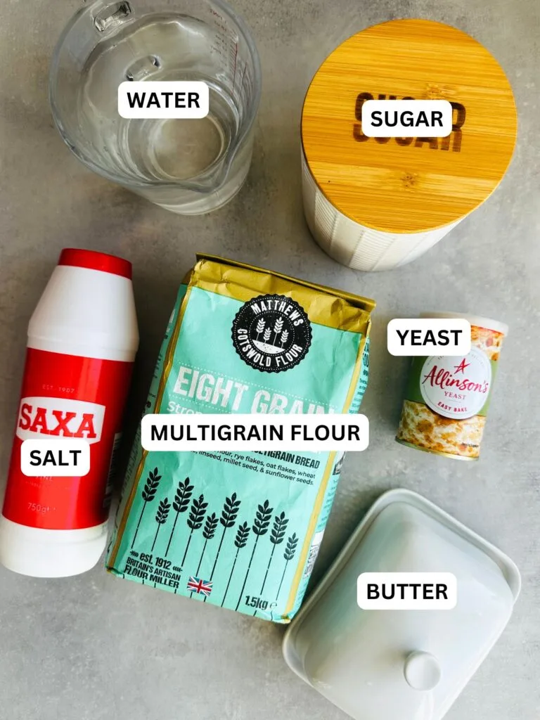 ingredients laid out for multigrain bread loaf made in the bread maker: water, sugar, salt, multigrain flour, yeast and butter