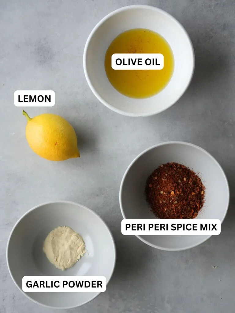ingredients laid out and labelled for peri peri paste: olive oil, lemon, garlic powder, peri peri spice mix
