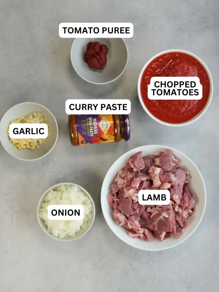 ingredients laid out and titled: tomato puree, chopped tomatoes, curry paste, garlic, onion, lamb