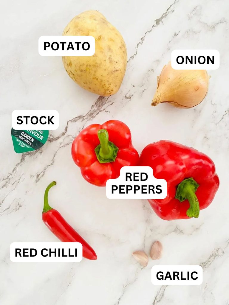 2 red peppers, 2 cloves garlic, 1 onion, 1 potato and 1 fresh red chilli ready to make a red pepper and chilli soup in a soup maker