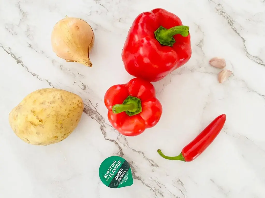 2 red peppers, 2 cloves garlic, 1 onion, 1 potato and 1 fresh red chilli ready to make a red pepper and chilli soup in a soup maker