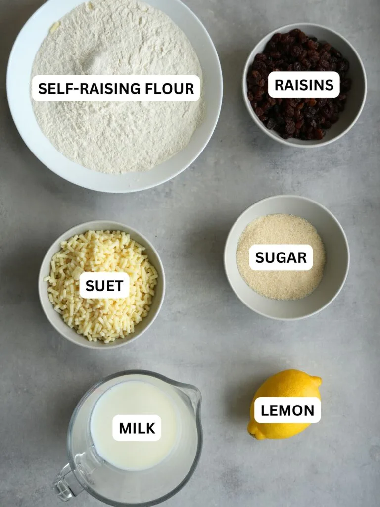 ingredients laid out and labelled for spotted dick: self raising flour, raisins, suet, sugar, milk and lemon