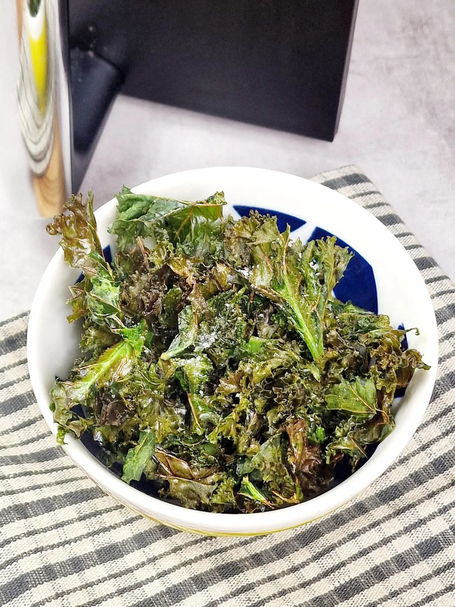kale chips in a bowl next to an air fryer