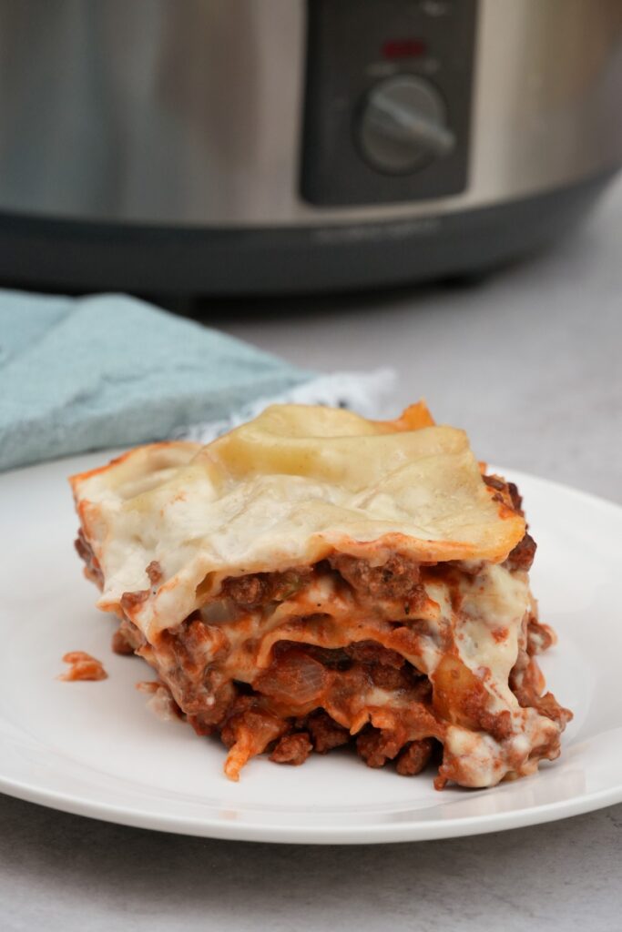 lasagne on plate up close with slow cooker behind it