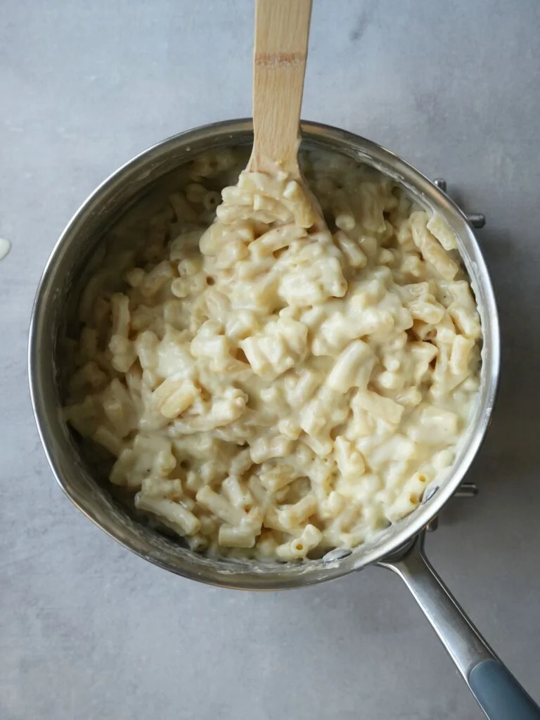 cooked macaroni in saucepan with cheese sauce mixed in