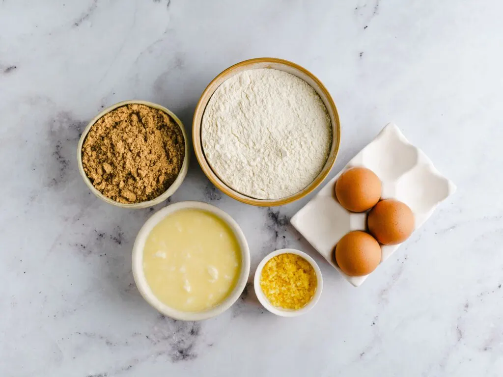 ingredients for Madeira cake laid out: flour, sugar, eggs. butter, lemon zest