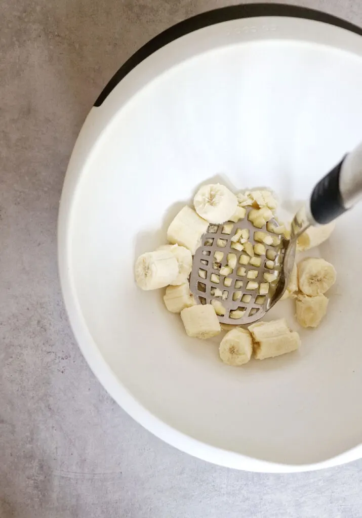 mashing bananas with a potato masher