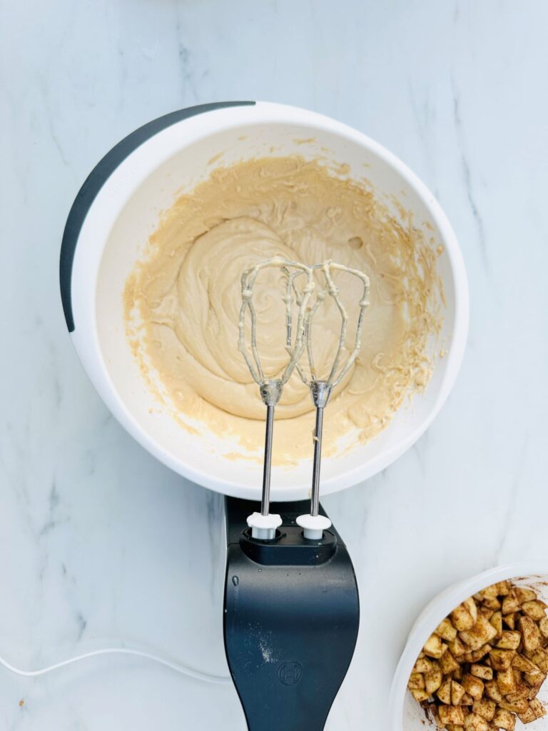 mixing apple cake batter with electric whisk