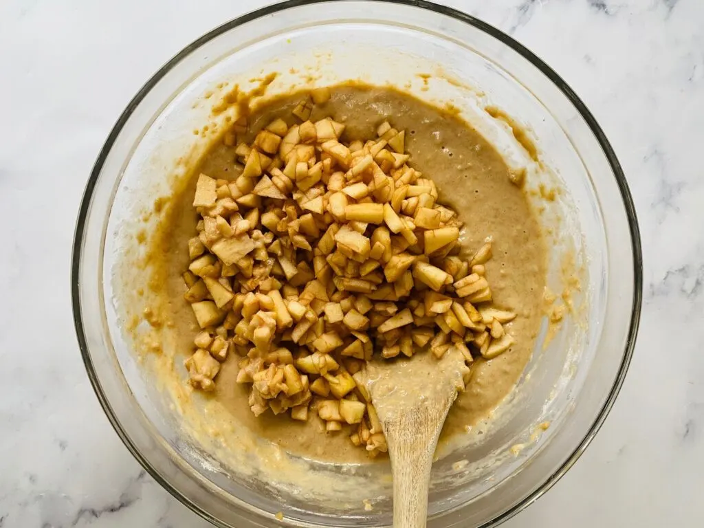 mixing chopped apples in with apple muffin batter