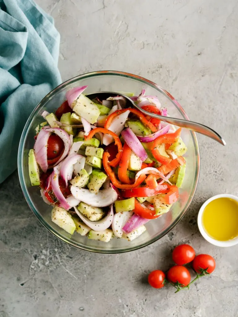 vegetables in a bowl with olive oil and seasoning ready for roasting