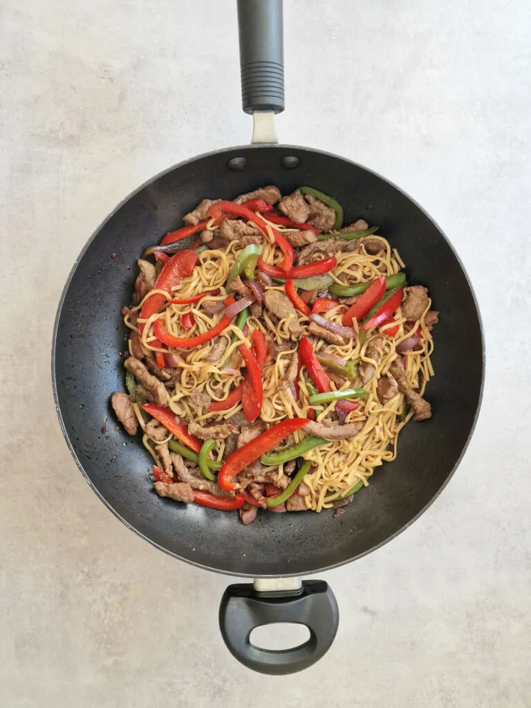 noodles vegetables and beef in fying pan to make stir fry