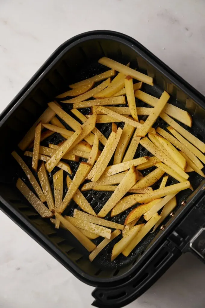 oiled and seasoned chips in air fryer basket