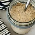 overnight oats in a glass jar with a spoon next to a coffee