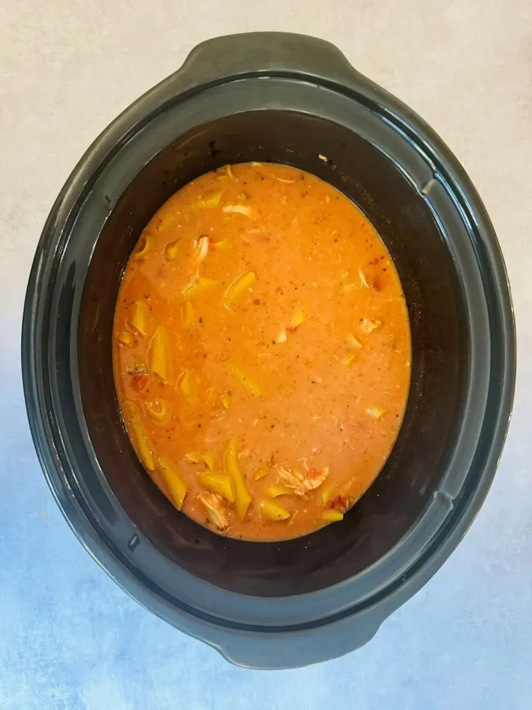 pasta submerged in sauce with chicken in slow cooker