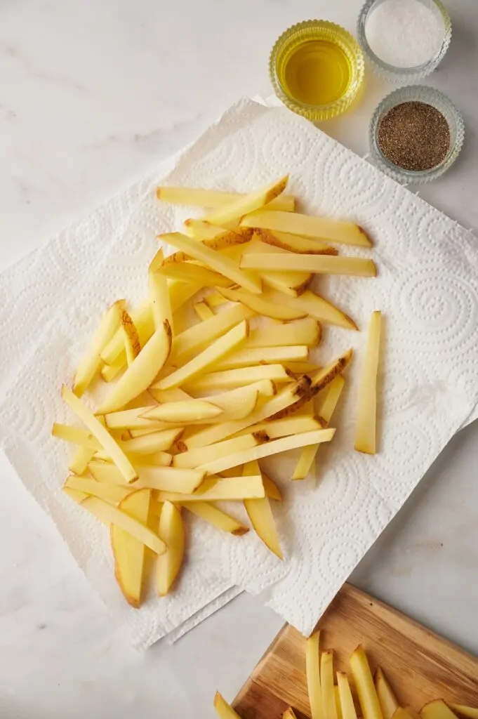 raw chips drying off on some kitchen roll next to oil and seasonings