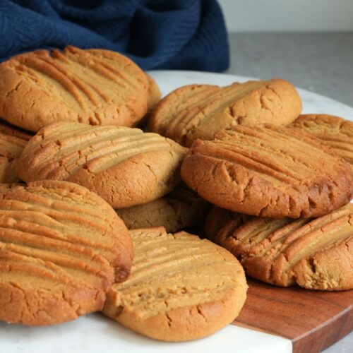 a pile of peanut butter cookies on a white and brown serving plate