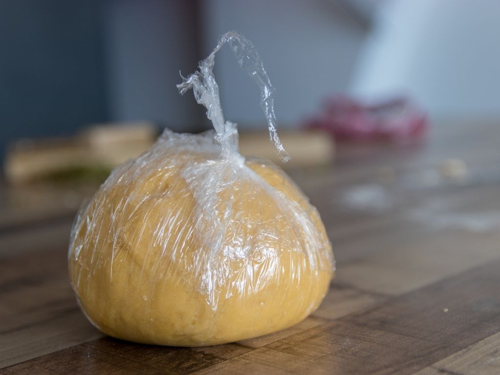 pizza dough wrapped in cling film ready to be frozen