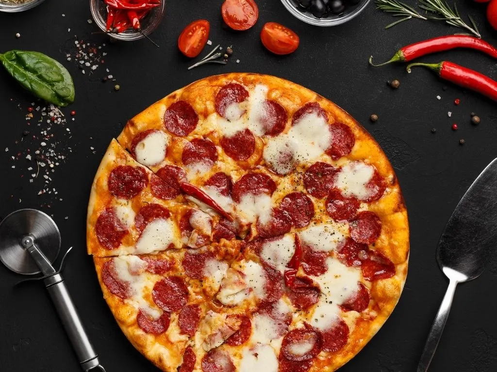 cooked pizza with pizza oven accessories next to it