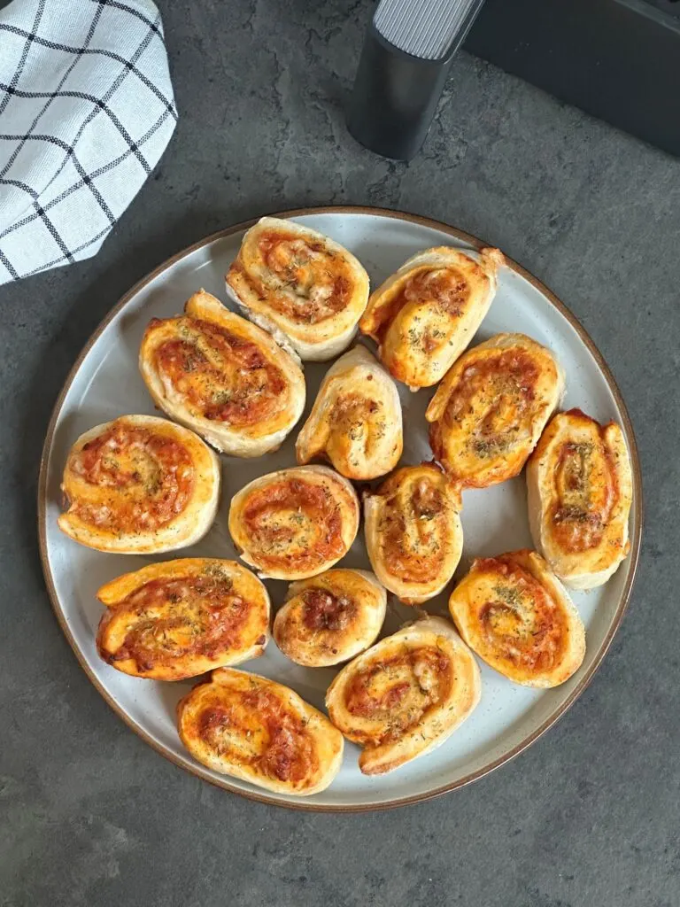 pizza rolls on a plate next to an air fryer