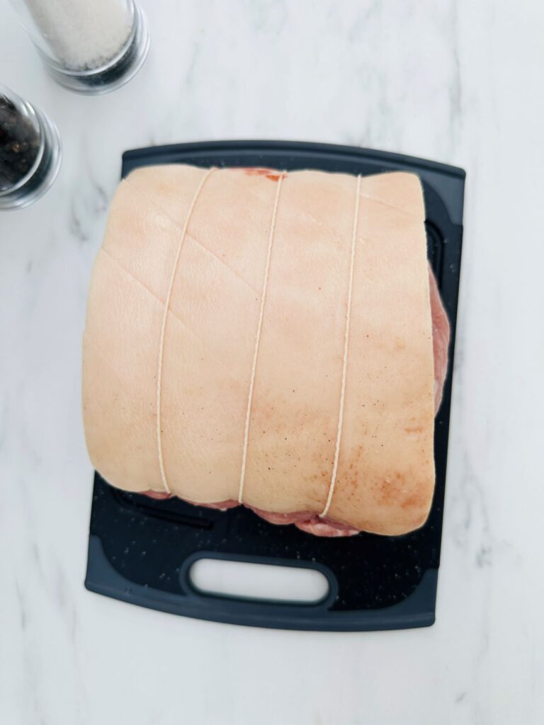 pork joint on chopping board with salt and pepper