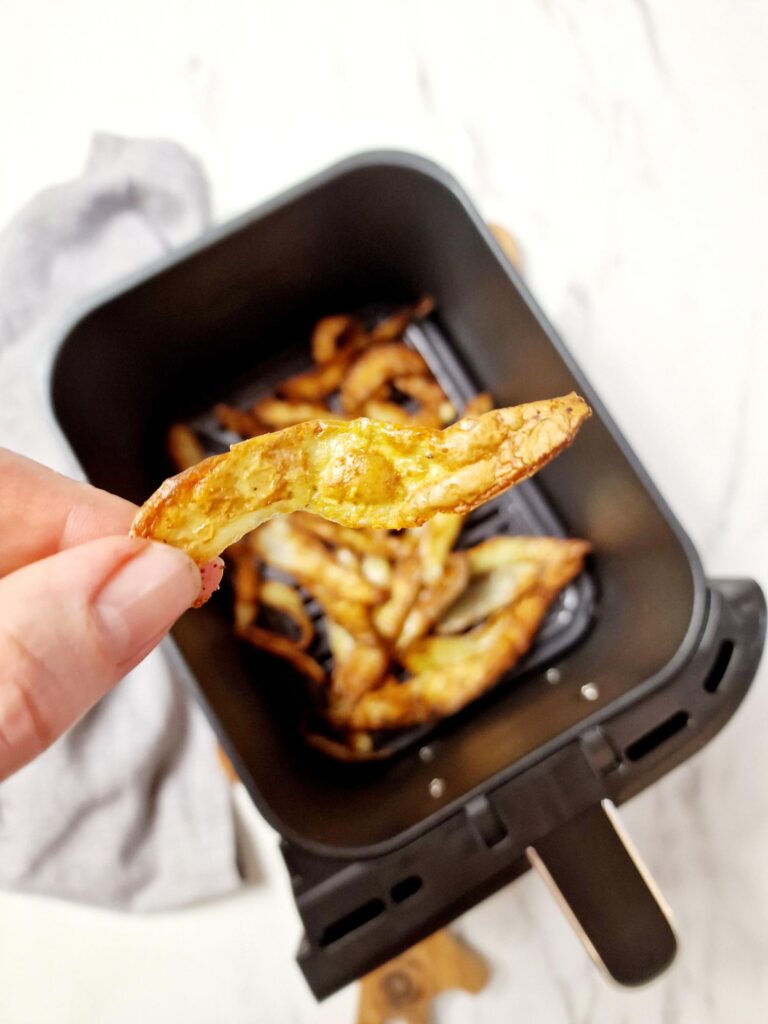 crispy potato peel above an air fryer basket