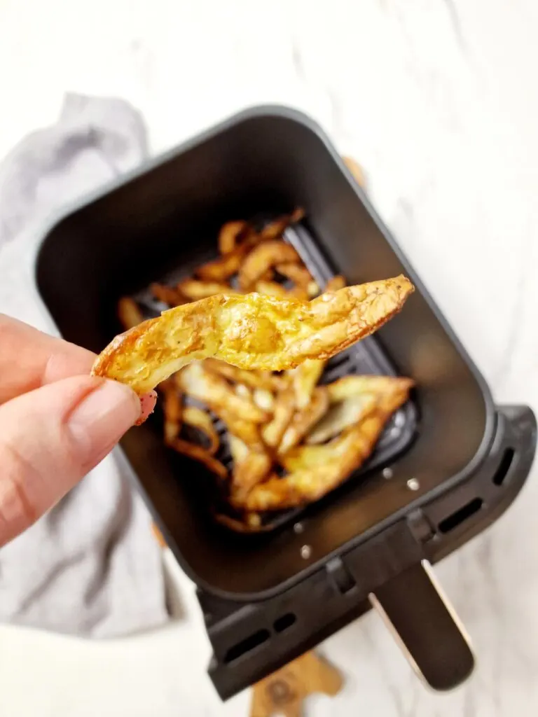 crispy air fryer peel above air fryer basket