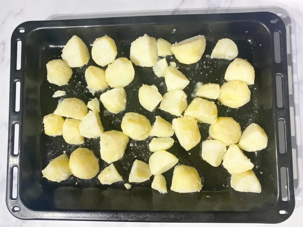 parboiled potatoes in shallow roasting tin ready to be roasted in the oven.