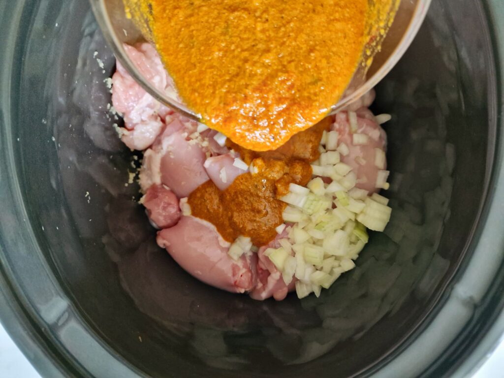 pouring korma sauce over chicken