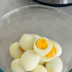 hard boiled eggs peeled and in a bowl sitting next to the ninja foodi 15-in-1
