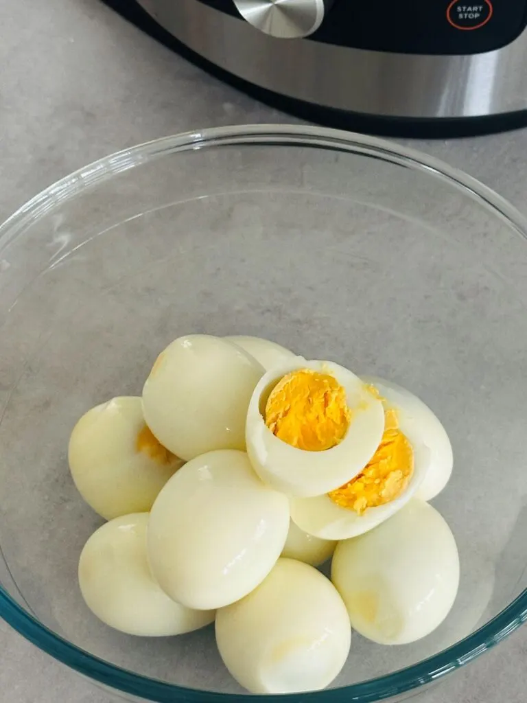 hard boiled eggs peeled and in a bowl sitting next to the ninja foodi 15-in-1
