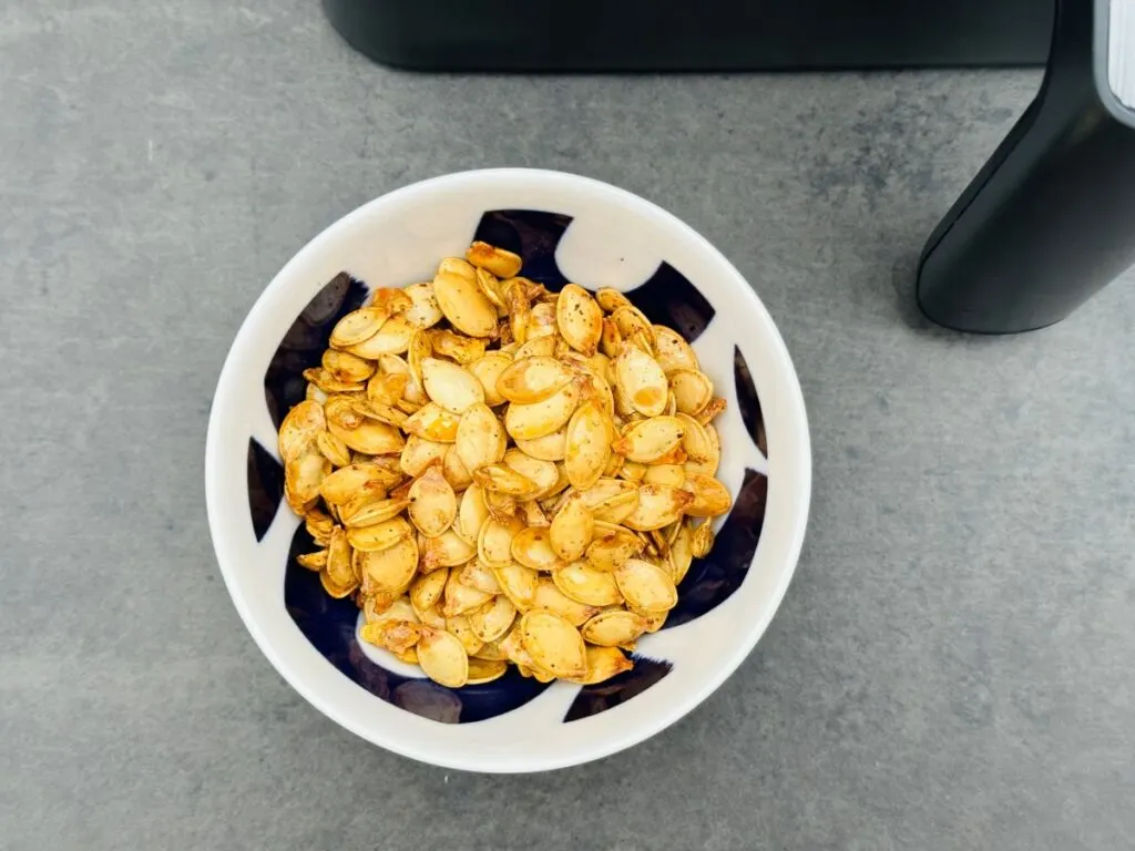 pumpkin seeds in bowl next to air fryer