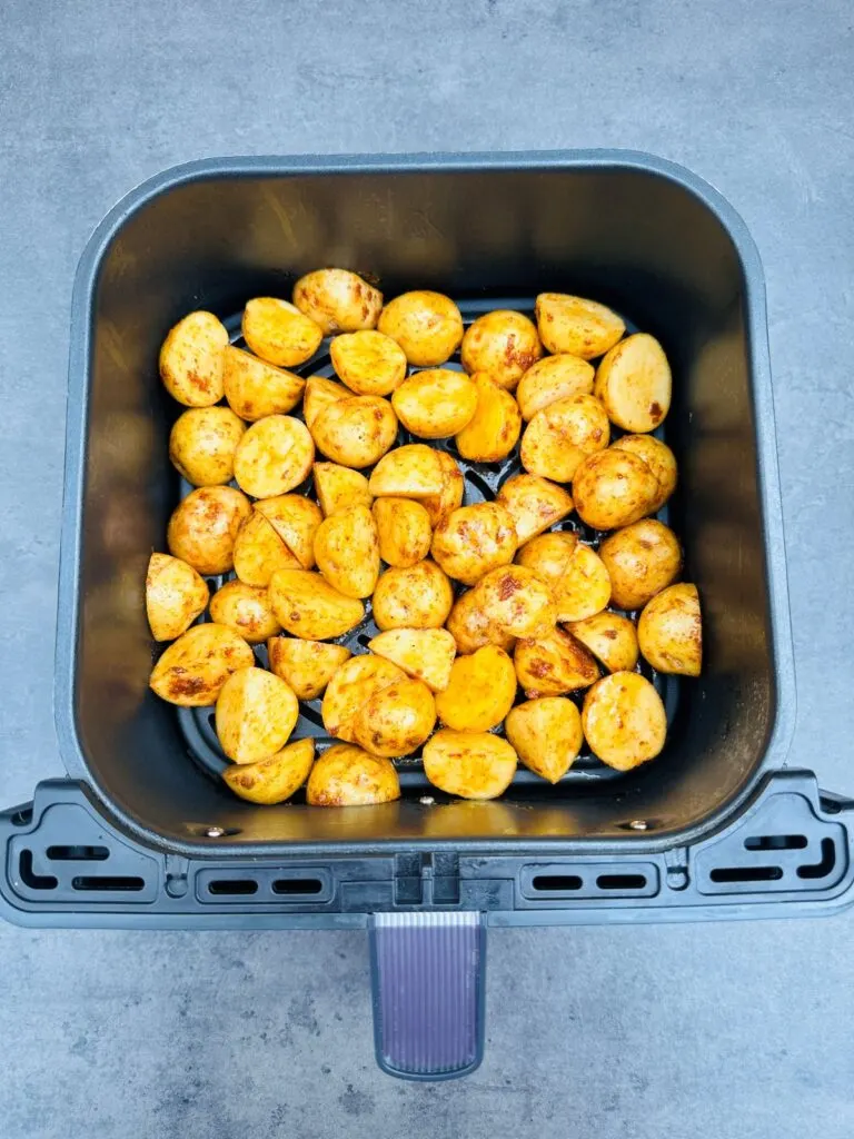 raw and seasoned new potatoes in air fryer basket