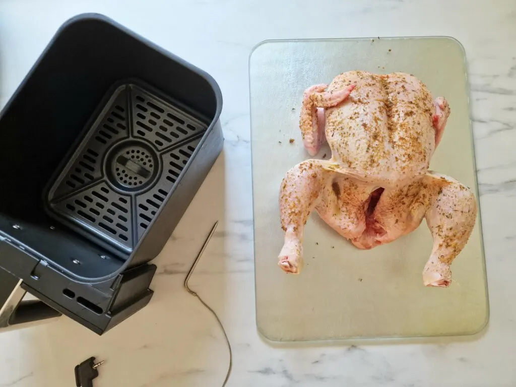 raw chicken next to air fryer basket with probe from Ninja Dual