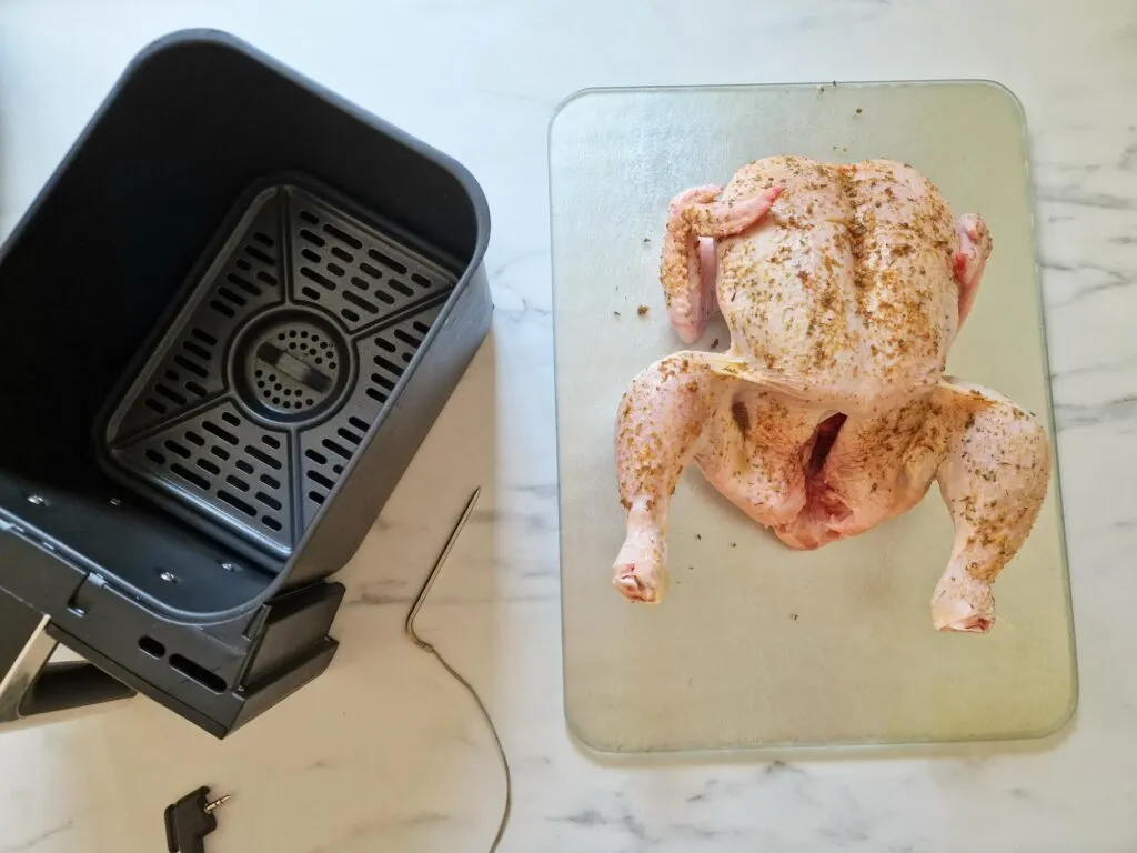 https://lianaskitchen.co.uk/wp-content/uploads/raw-seasoned-whole-chicken-next-to-air-fryer-basket--1024x768.jpg.webp